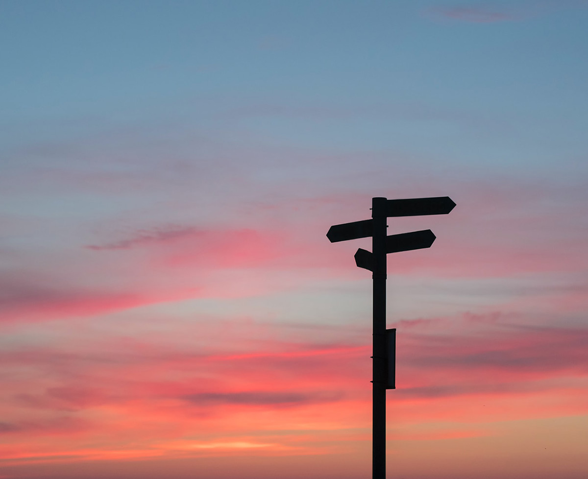Photo showing a silhouette of a directional sign at sunset